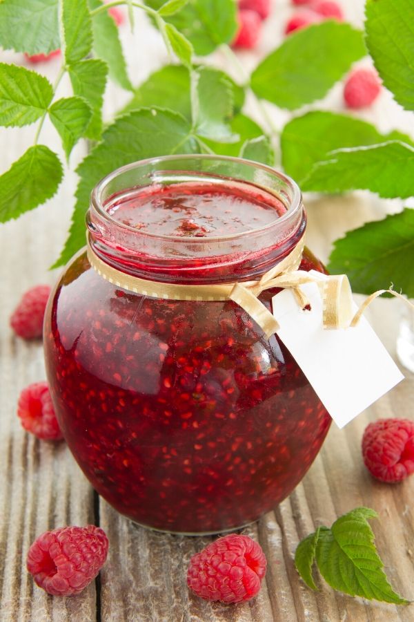 a small glass jar filled with homemade raspberry jam with prosecco and passionfruit 