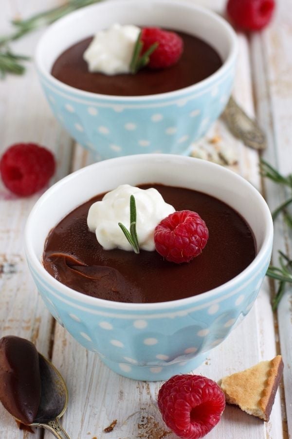 Selbstgemachter Schokoladenpudding mit echter Schokolade und Kakao serviert mit Sahne, Rosmarin und Himbeeren