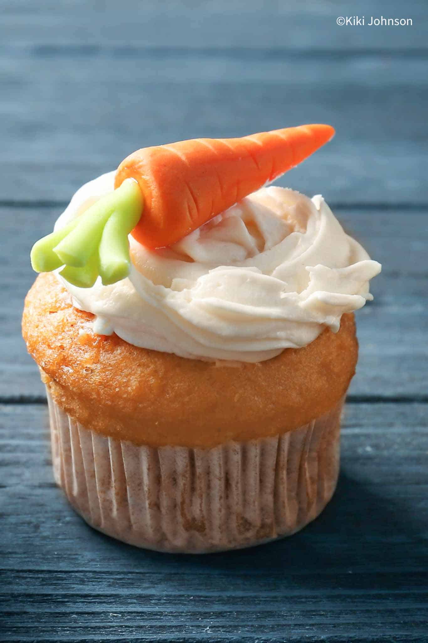 a carrot banana muffin topped with a swirl of healthy sugar-free quark frosting and a marzipan carrot 