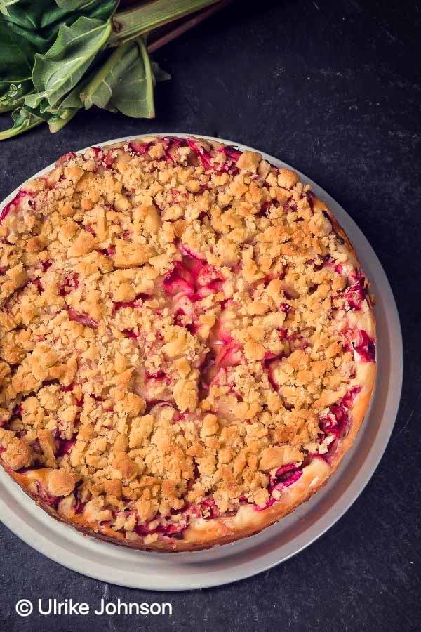 overhead shot of a German raspberry and rhubarb crumble cake with streusel topping