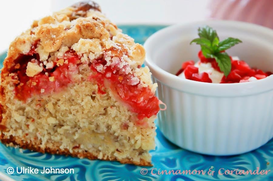 a slice of raspberry and rhubarb crumble cake on a blue plate served with sour cream