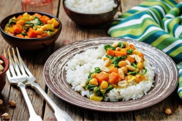 a plate with vegan chickpea pumpkin curry with coconut milk served over rice 