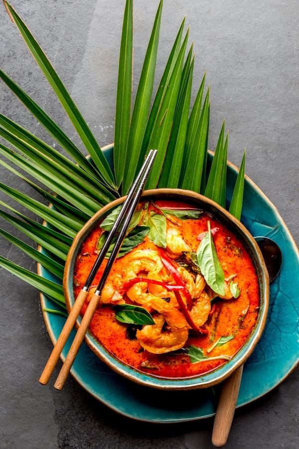 Brazilian Coconut Milk Shrimp Stew served in a blue bowl with a spoon on the side 