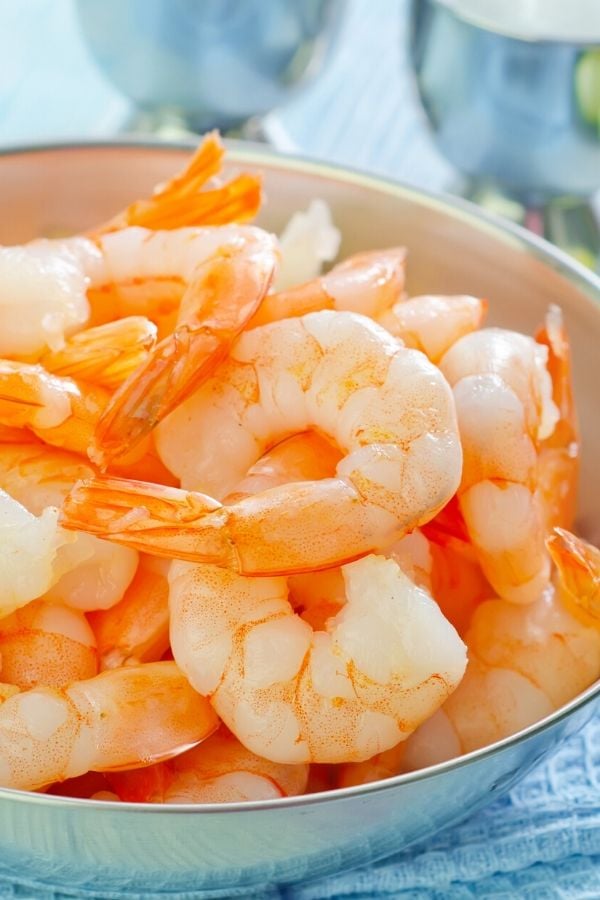 peeled shrimp with tails on in a bowl ready for being added to shrimp stew 