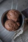 two scoops of dark chocolate ice cream with rum in a metal cup