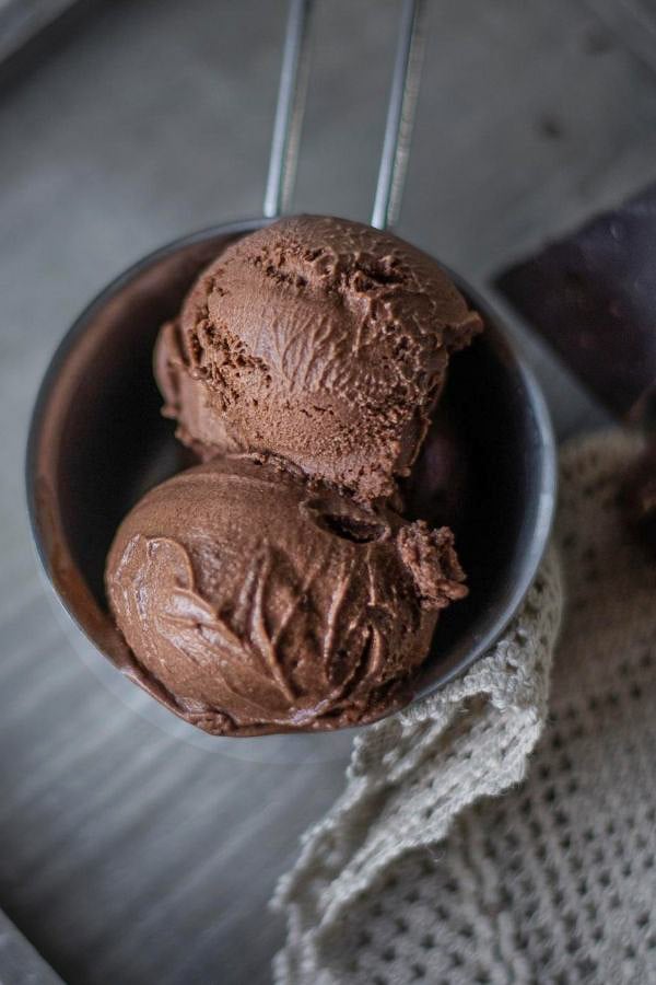 two scoops of dark chocolate ice cream with rum in a metal cup 