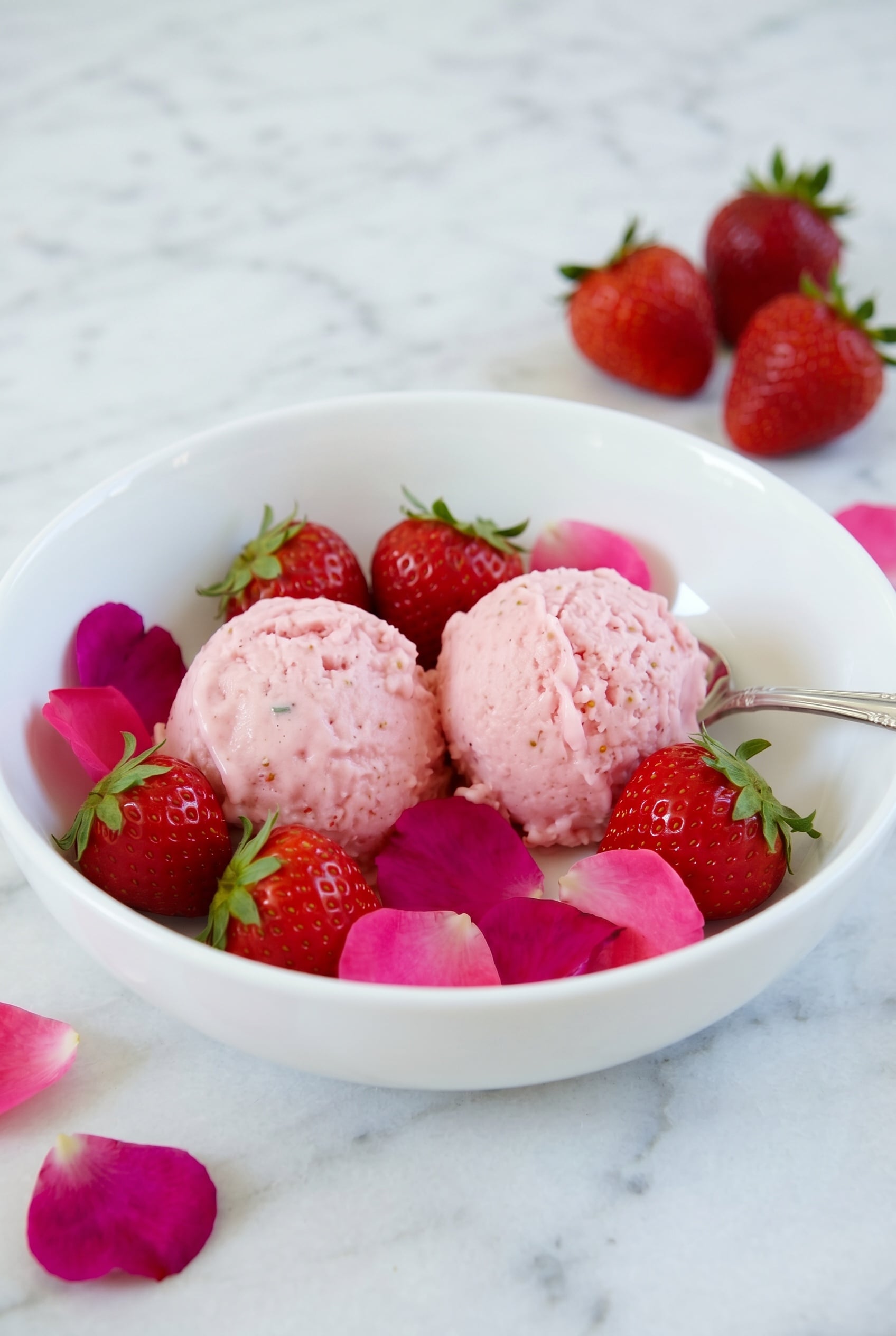 two scoops of strawberry rose ice cream served in a white bowl