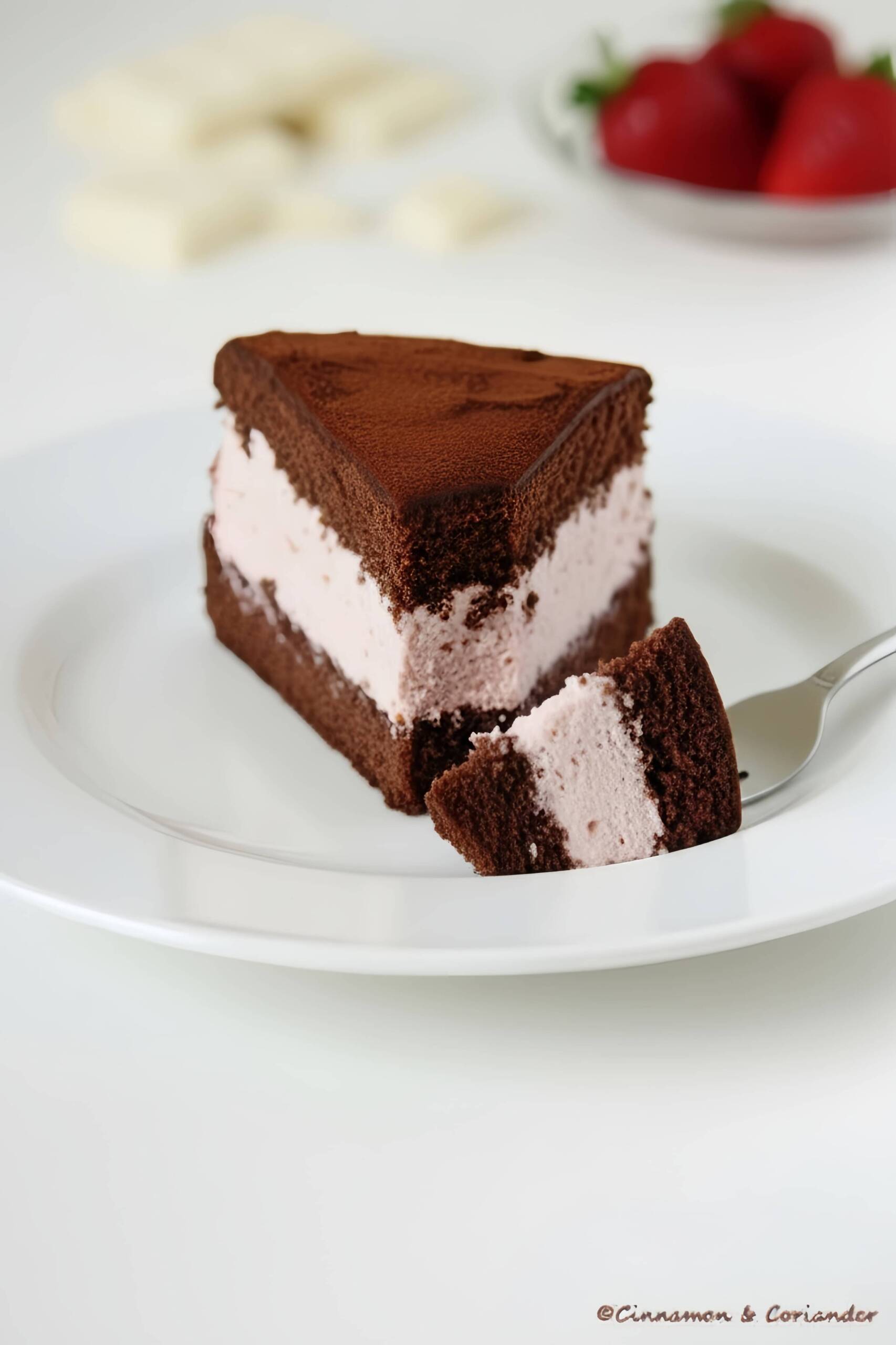 ein Stück Erdbeer Trüffel Torte mit einer Kuchengabel, dahinter ein Teller mit Erdbeeren