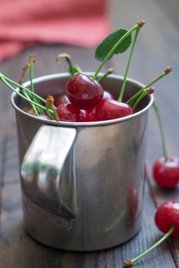 sour cherries in a metal cup on a kitchen counter 