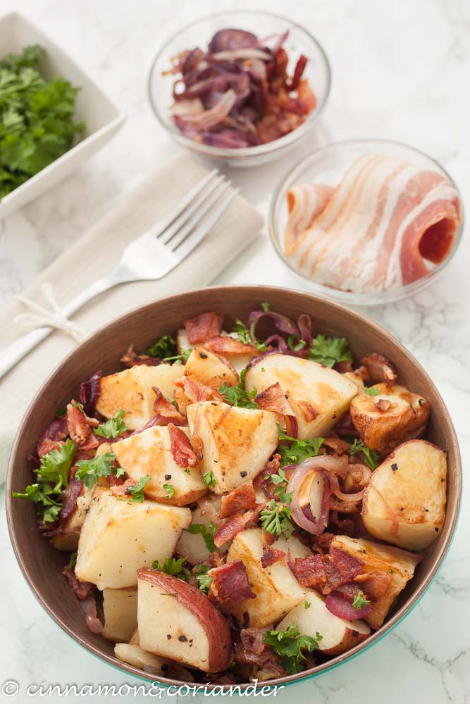 German Potato Salad with warm Bacon Vinaigrette and fried onions in a bowl with a fork on the side