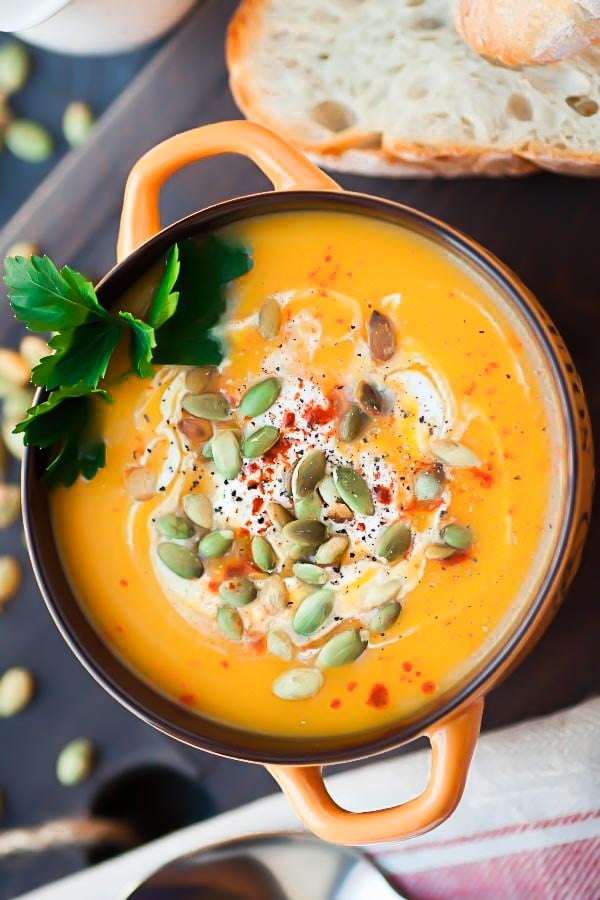 overhead shot of a pot with easy butternut squash soup with orange and ginger topped with pepitas 