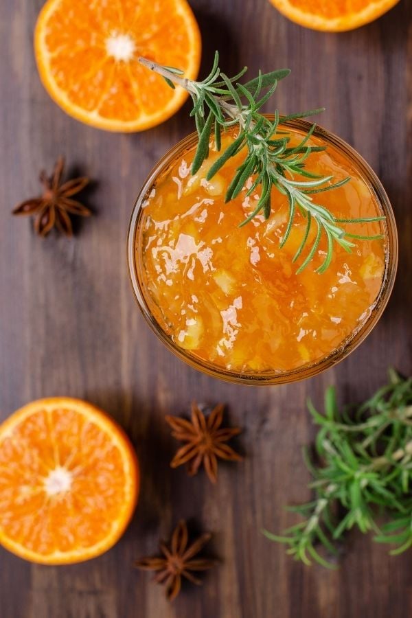 overhead shot of a jar of homemade orange marmalade with rosemary and star anise