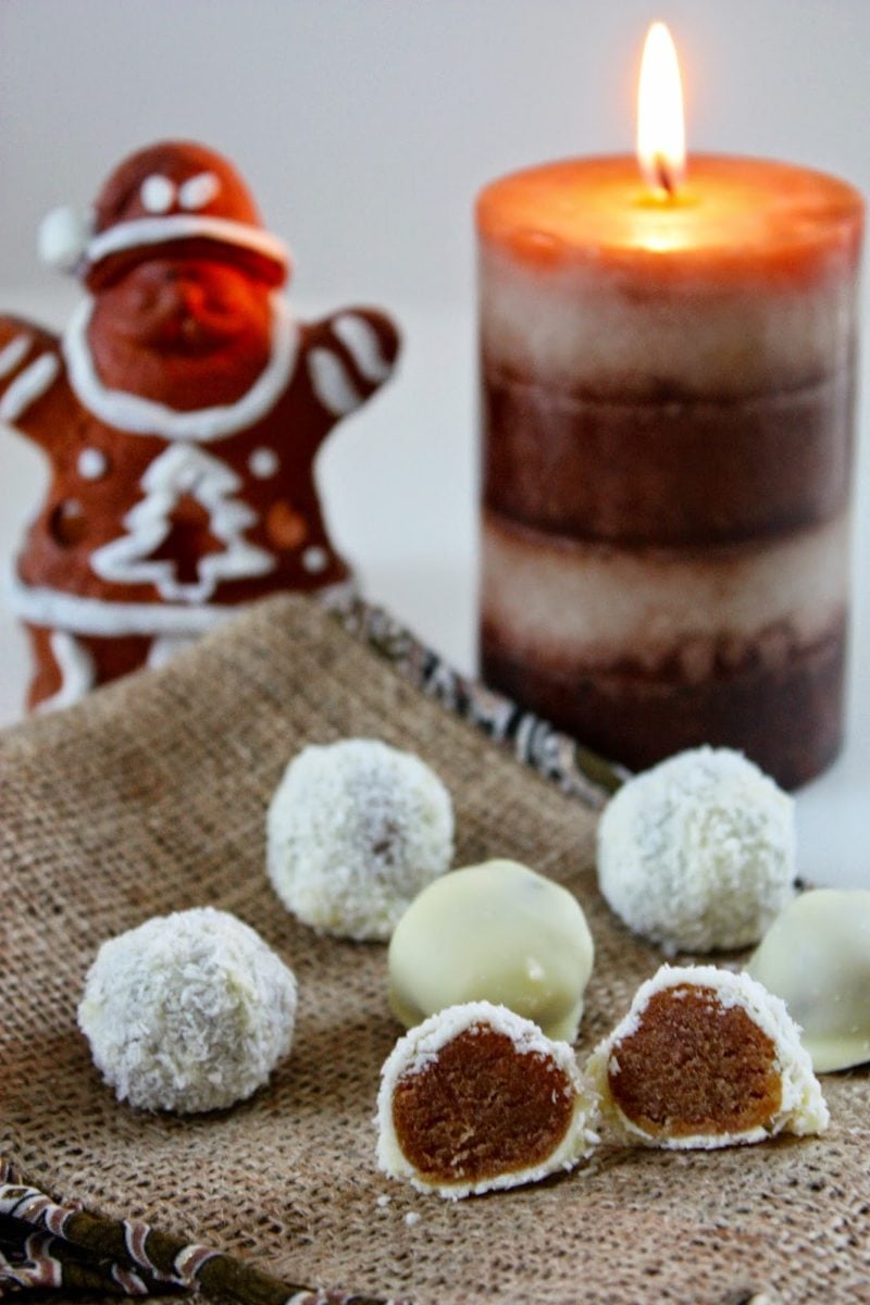 Spekulatius Pralinen mit Marzipan und weißer Schokoladenglasur mit einer Kerze im Hintergrund