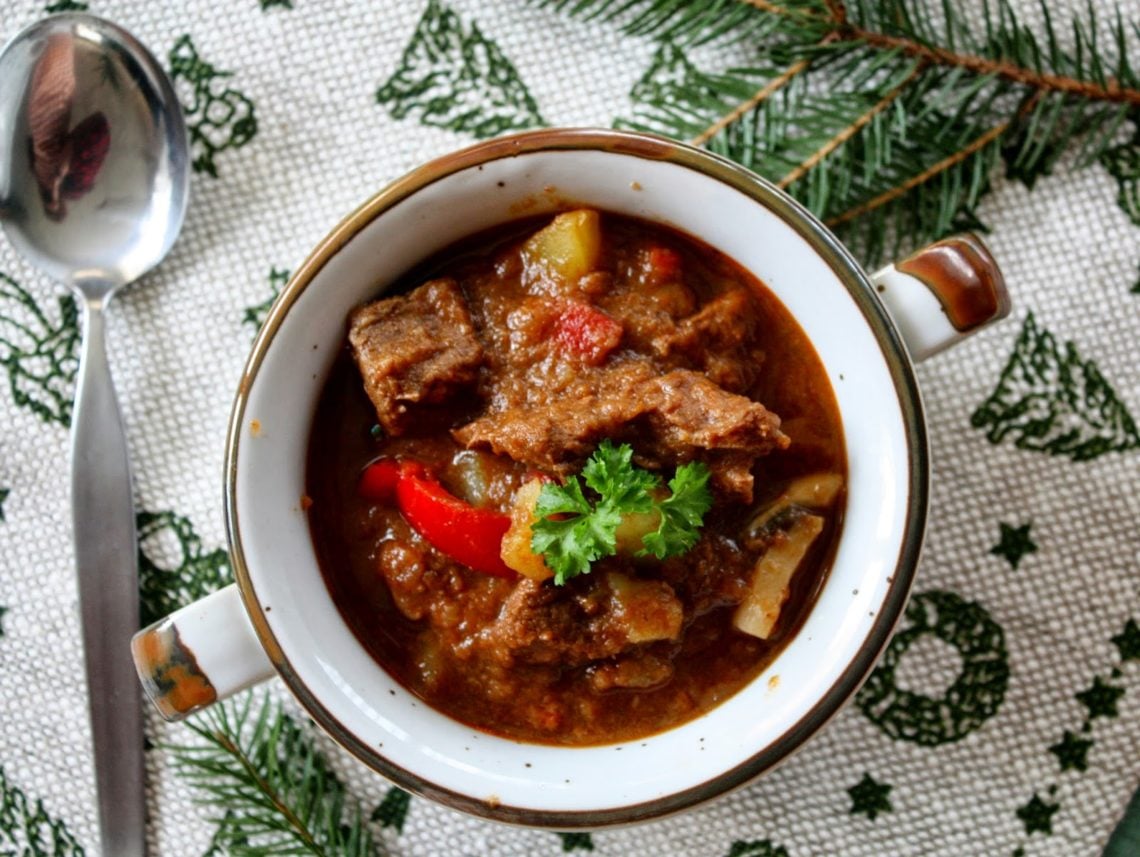 traditional goulash with beef served in a soup bowl with some parsley on top 