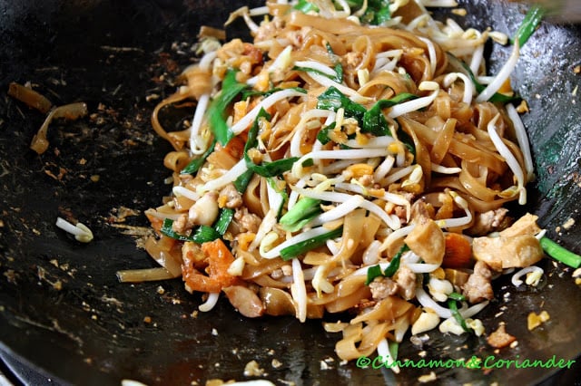 authentic pad thai being prepared in a hot black skillet
