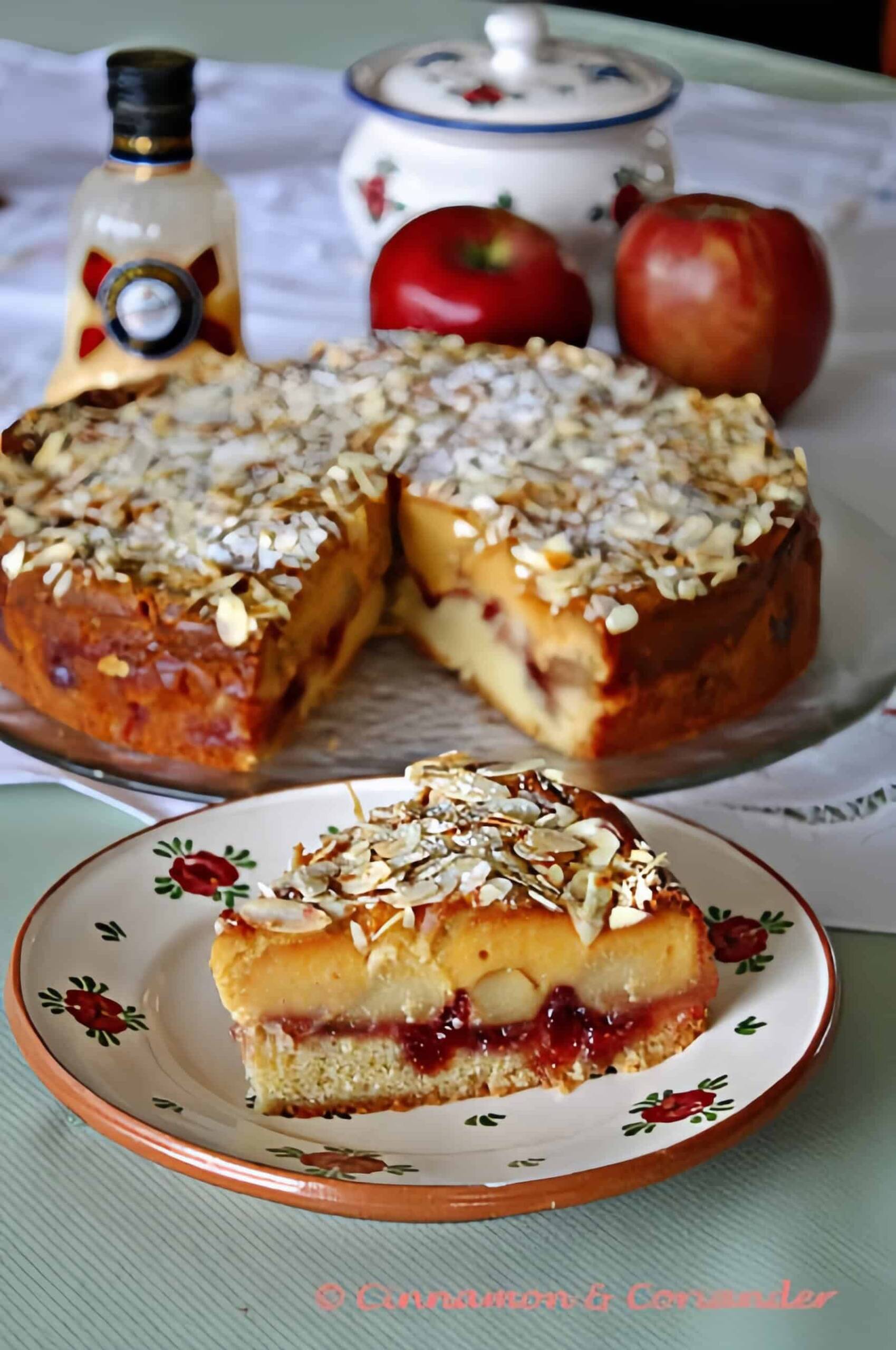 ein Stück Omas saftiger Apfelkuchen mit Eierlikör und Marzipan - Guss auf einer herbstlichen Landfrauen Kuchentafel mit einer Flasche Eierlikör im Hintergrund. 