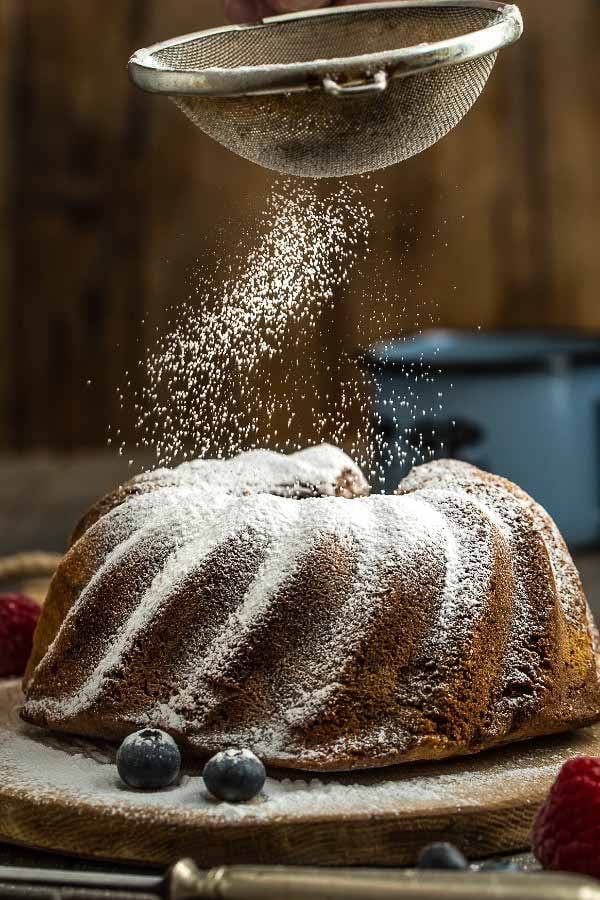 Puderzucker wird über Omas Nusskuchen gestreut