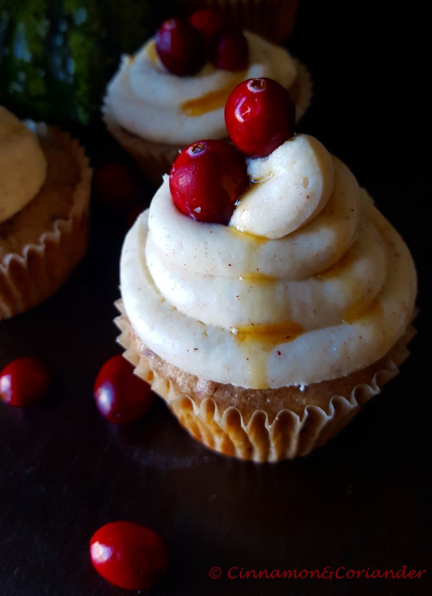 side view of a moist cranberry chai muffin topped with maple cream cheese frosting