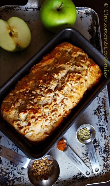 Quick Apple Bread with Rosemary and Sunflower Seeds in a loaf pan with some apples on the side