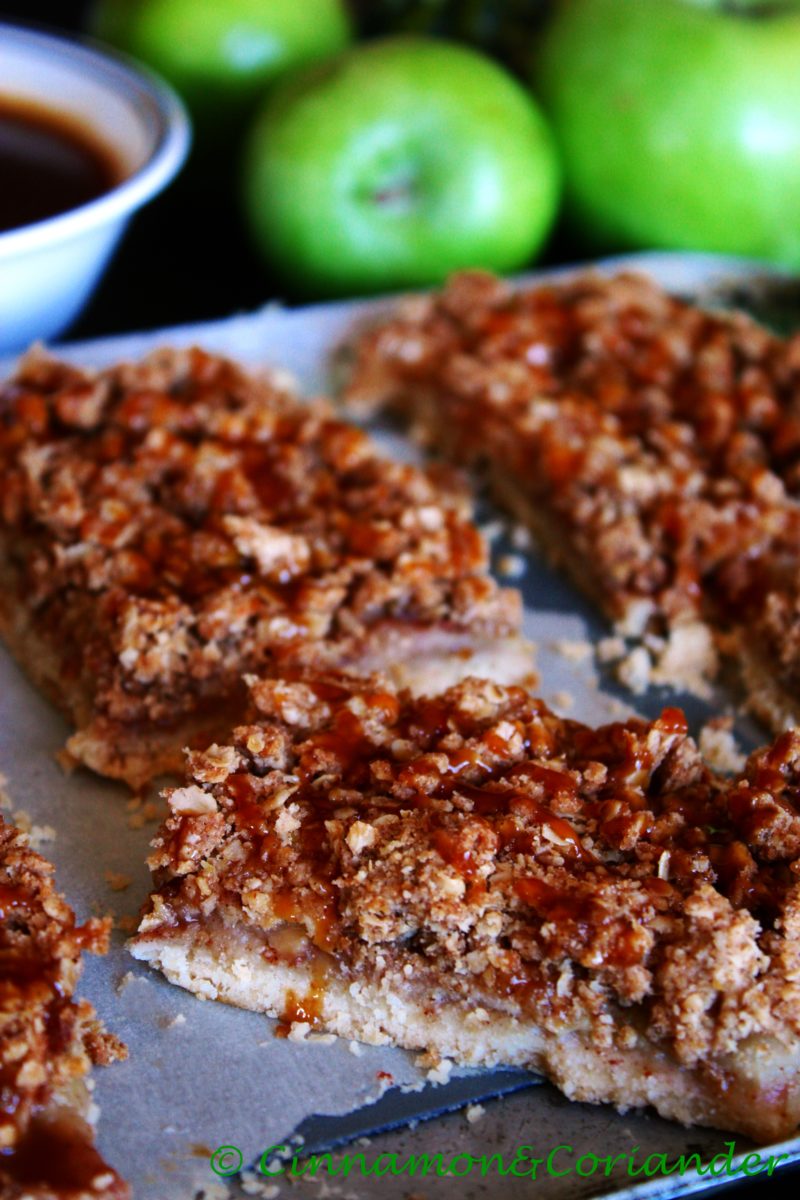 close-up of salted caramel apple pie bars on a silver baking tray with some caramel running down the sides of the bars