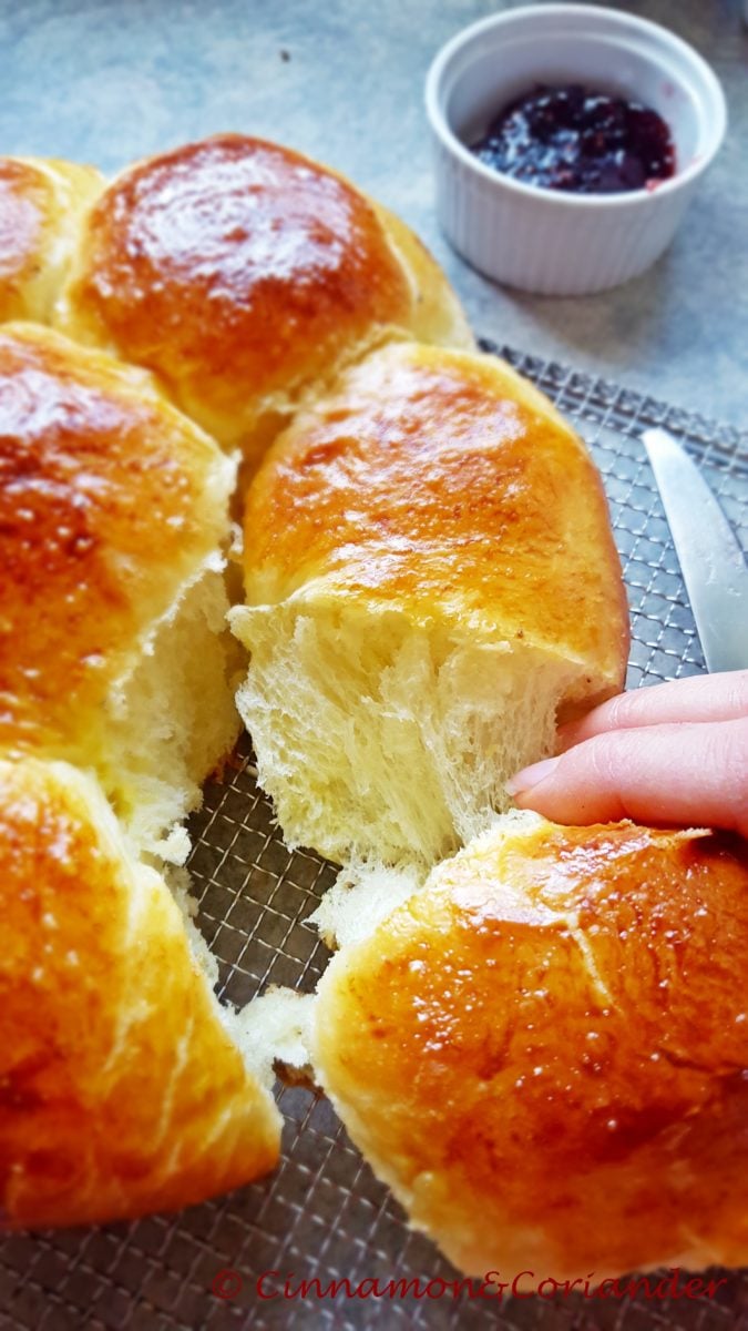 a brioche bun being torn off a freshly baked brioche loaf