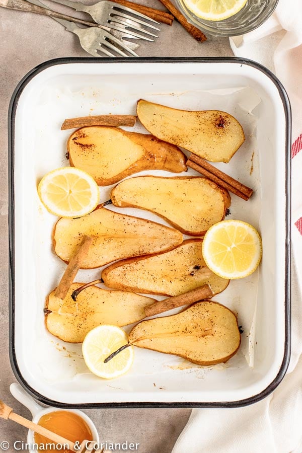 a white casserole dish with baked pear slices in vanilla honey lemon syrup