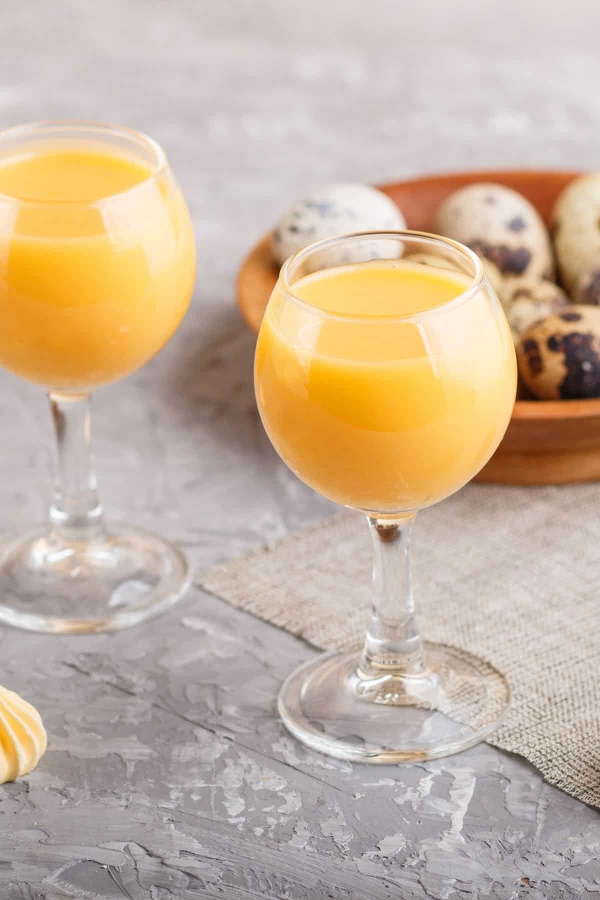 two glasses of homemade German Egg liqueur with quail eggs in the back 