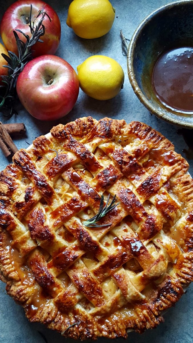 salted caramel apple pie with a golden lattice topping and a twig of rosemary on top