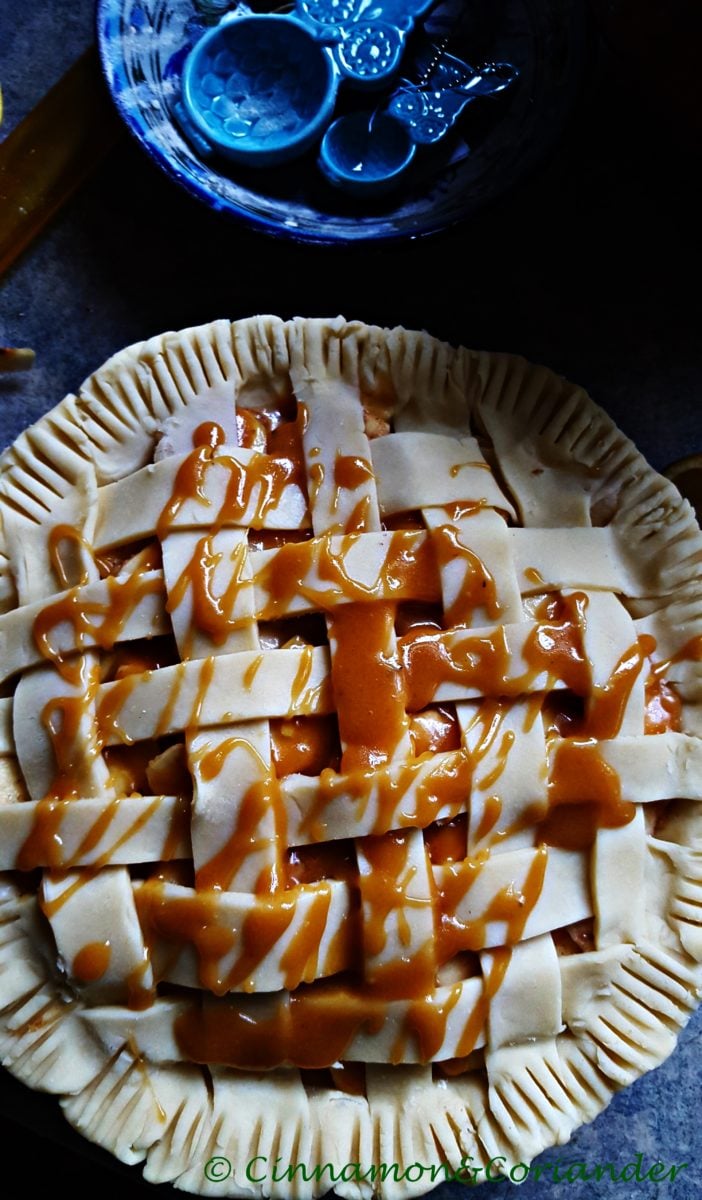 unbaked salted caramel apple pie with caramel sauce drizzled on top of the lattice topping 