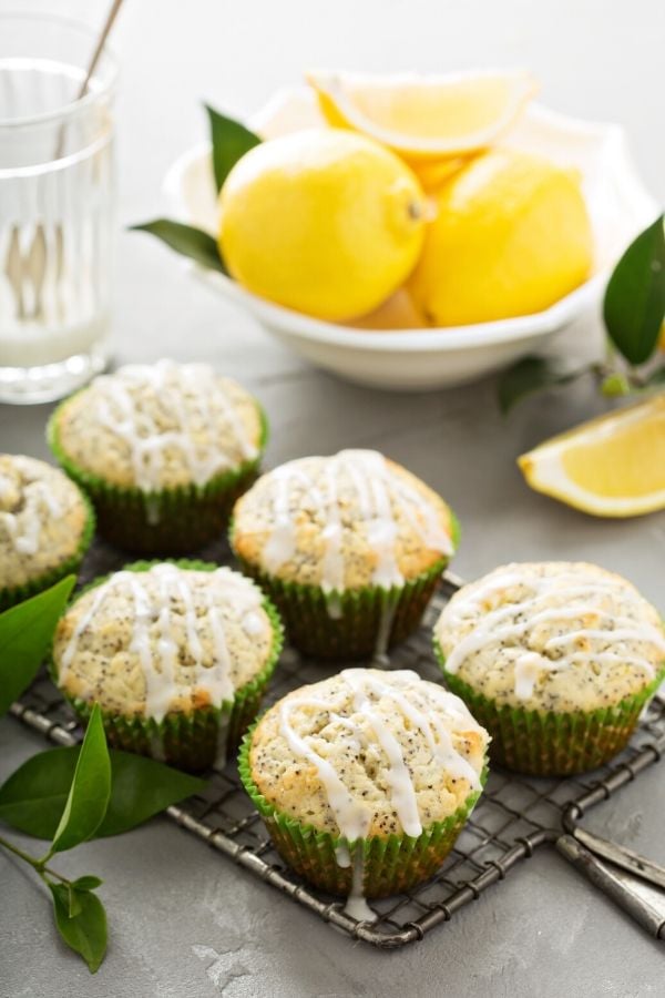 overnight lemon poppyseed muffins drizzled with lemon glaze on a metal rack