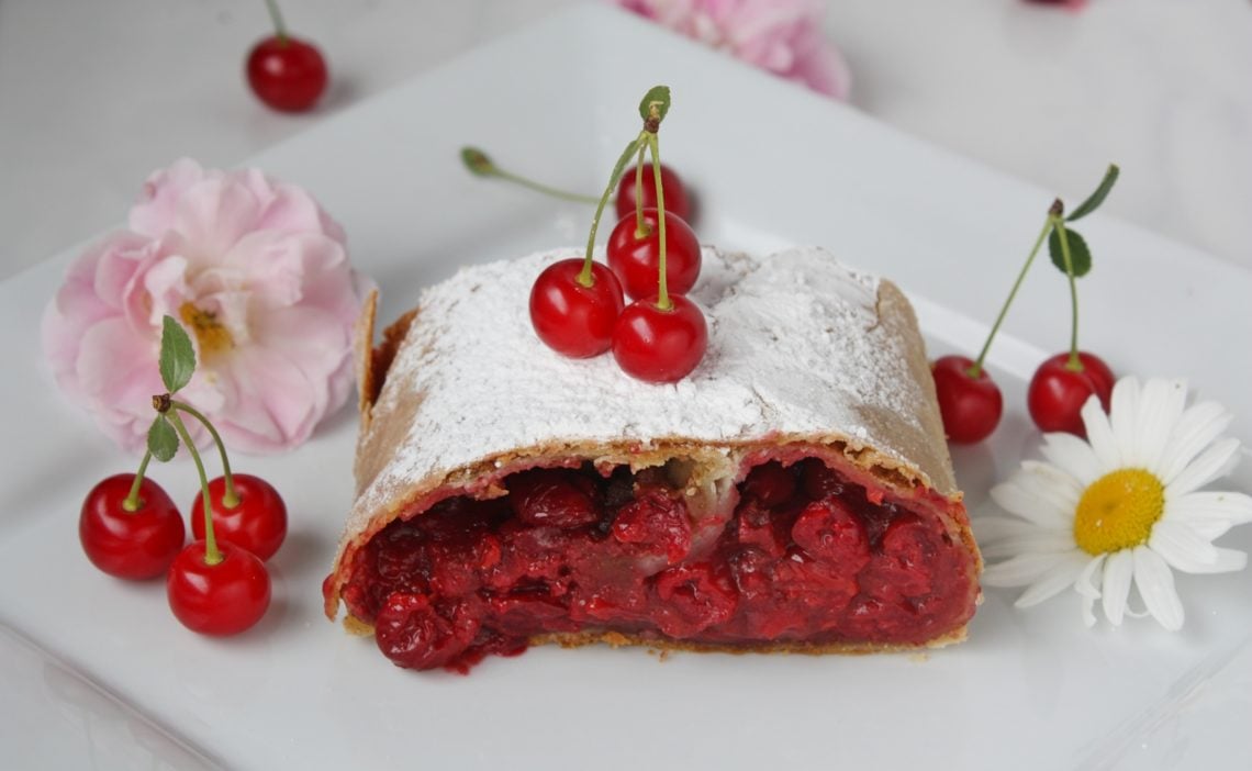 ein Stück Kirschstrudel mit selbstgemachtem Strudelteig auf einem weißen Teller