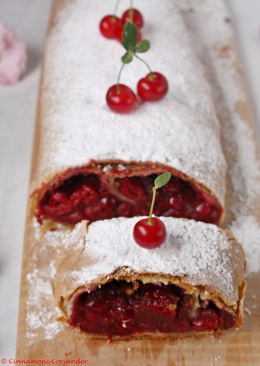 selbstgemachter Kirschstrudel mit Puderzucker bestäubt auf einer Kuchenplatte