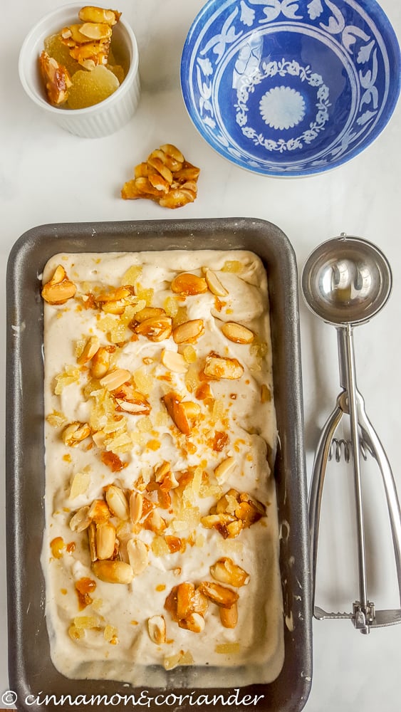 Thai Peanut Ice Cream with Caramelized Peanuts and Candied Ginger in a rectangle dish with an ice cream scoop on the side 