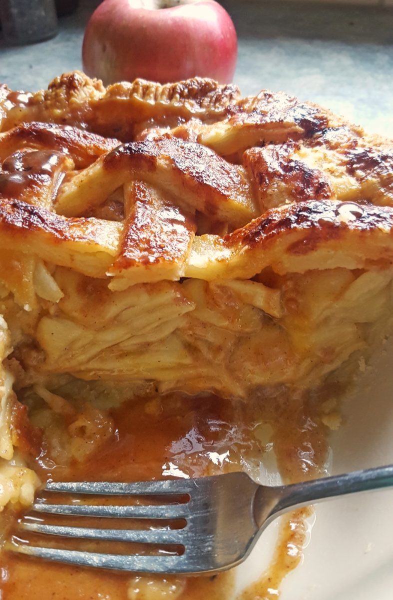 side view of Salted Caramel Apple Pie with Rosemary Infused Salted Caramel Sauce with a fork in the pie dish