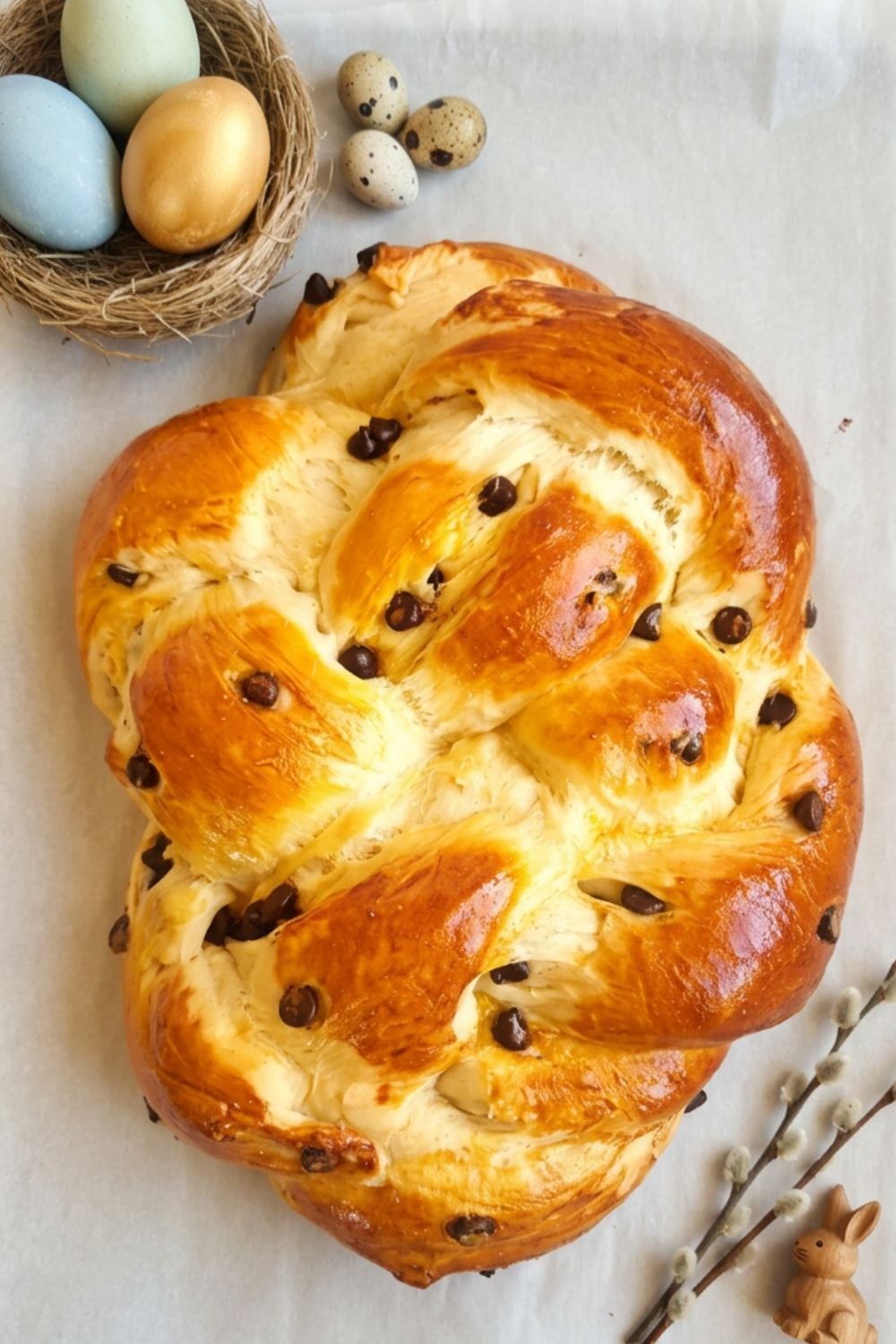ein ganzer Brioche Hefezopf mit Schokostückchen auf einem Oster Brunch Tisch mit Oster Eiern