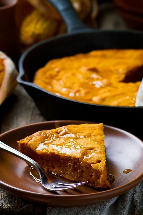  a slice of pumpkin cornbread drizzled with maple syrup on a brown plate