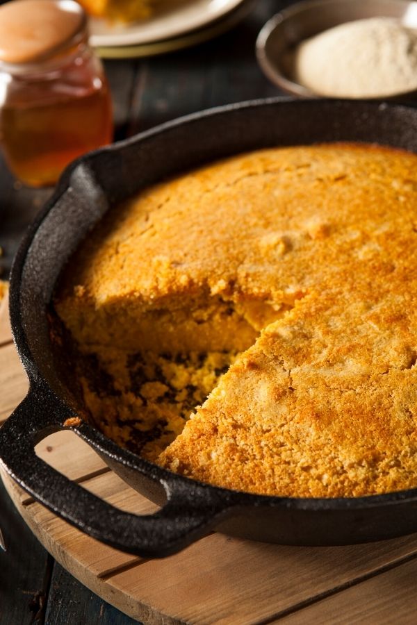 pumpkin cornbread in a skillet with one slice cut out 