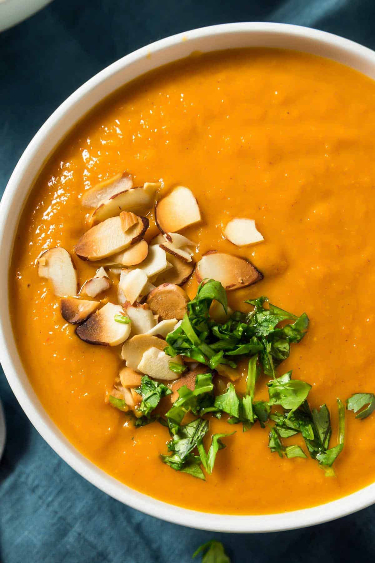 a plate of vegan sweet potato soup topped with cilantro and almonds