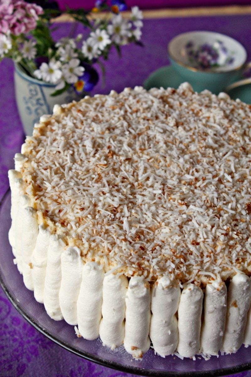 Best Raffaello Cake decorated with cream and toasted coconut on a cake stand