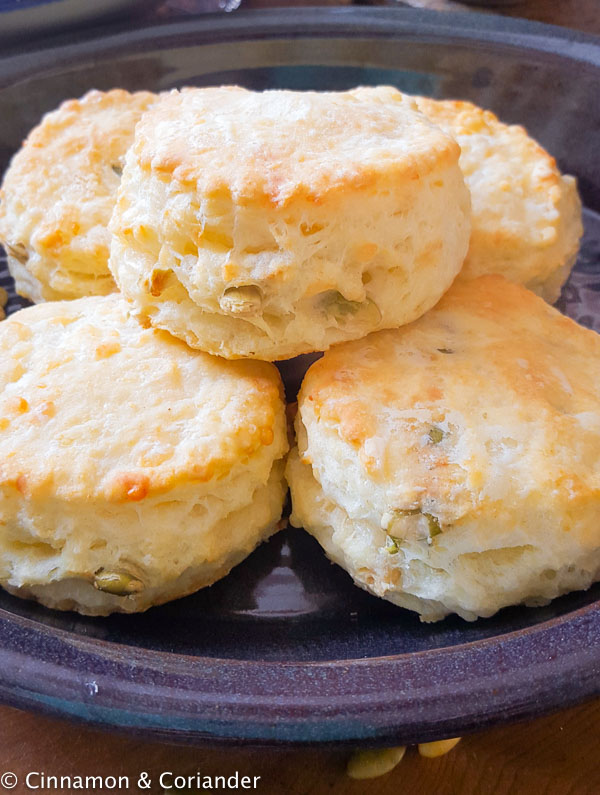 close-up on a plate of homemade flaky buttermilk biscuits with grated cheddar and pumpkin seeds