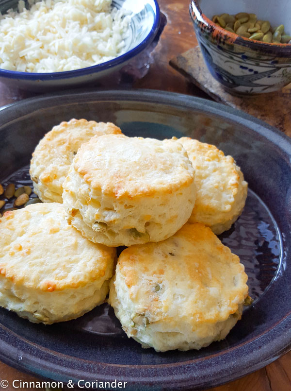 overhead shot of a blue plate loaded with flaky buttermilk biscuits with cheddar cheese