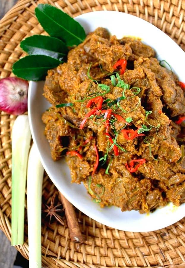 overhead shot of beef rendang with lemongrass and lime leaves on the side