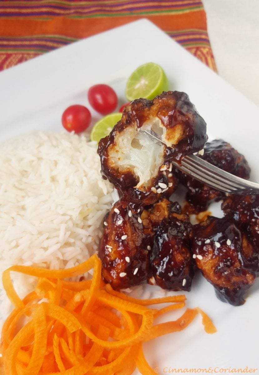 Vegan General Tso Cauliflower served on a plate with rice and a carrot salad