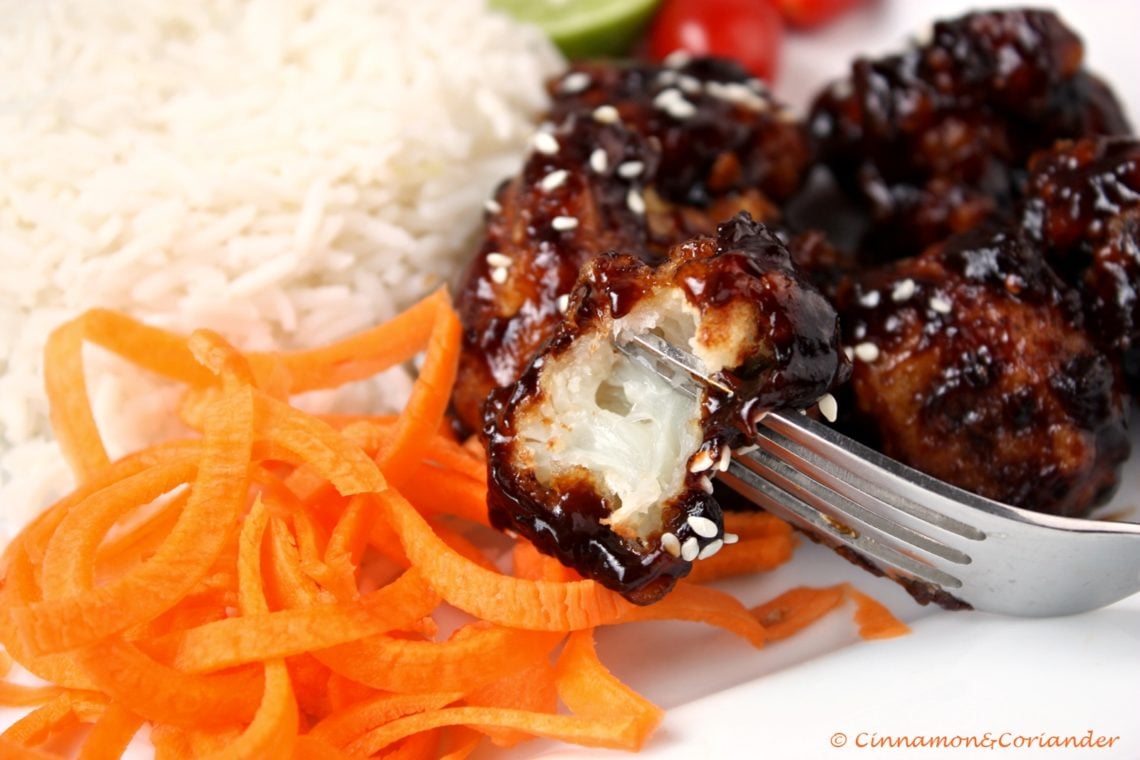 a crunchy piece of General Tso's Cauliflower coated in sweet and sour sauce balanced on a fork