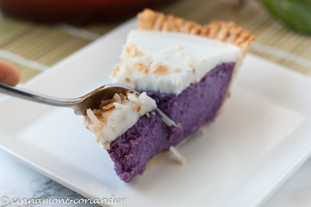 a slice of purple sweet potato pie on a white plate with a fork tucking into it