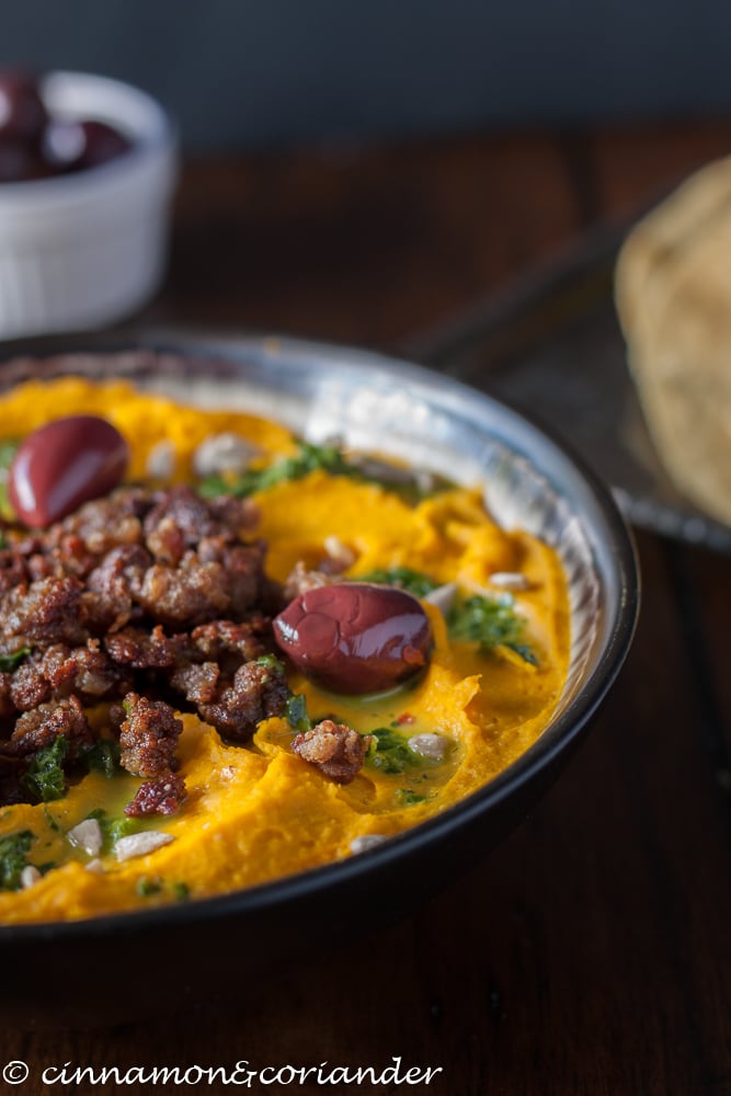  a bowl of Roasted Kabocha Squash Hummus with Lamb and Lemon Parsley Sauce on top 