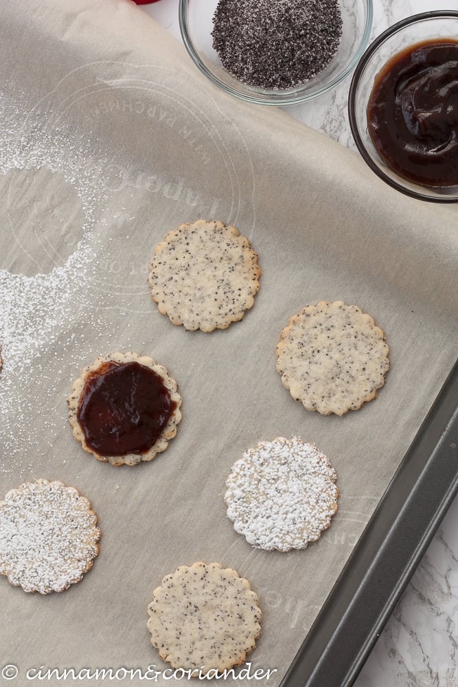 Poppy Seed Marzipan Sandwich Cookies with Plum Jam on a lined baking tray