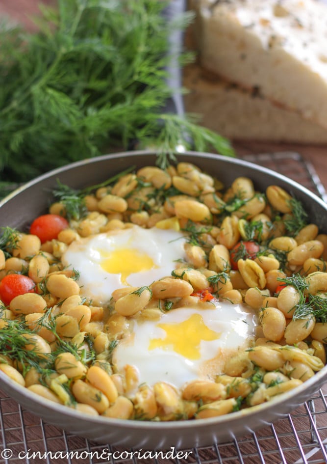 Iranian Bean Stew baghali ghatogh with poached eggs in a black skillet