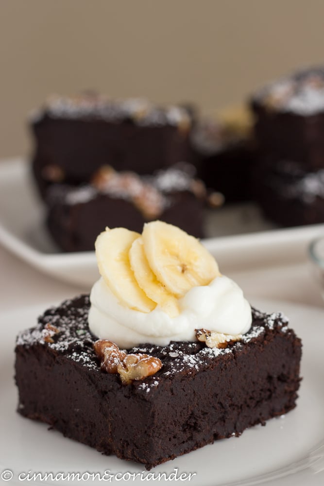 gesunder Brownie aus Bohnen mit einem Klecks Kokossahne und Bananenscheiben dekoriert