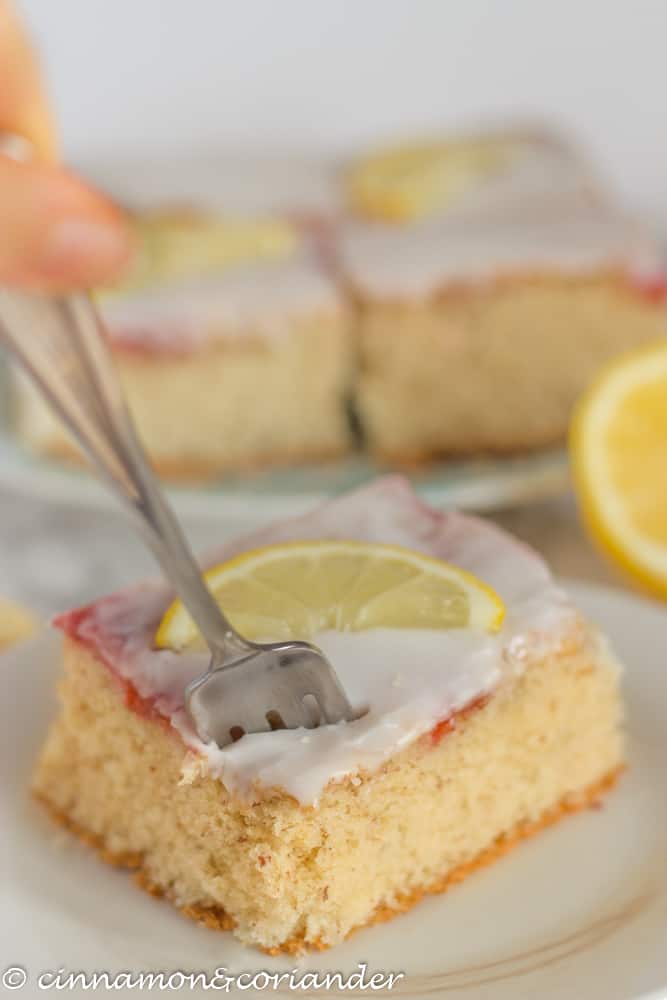 gluten free eggnog sheet cake with lemon icing on a plate with a fork on the side